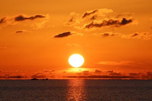 A breathtaking ocean sunset with a vibrant orange sky, perfect for serene backgrounds.