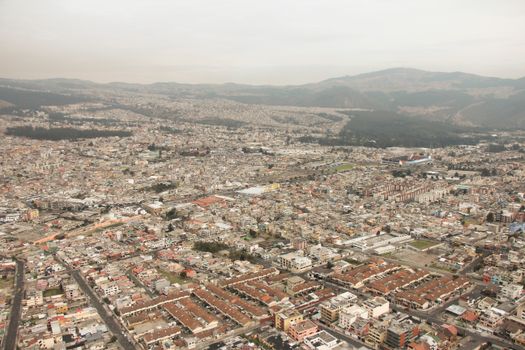 Expansive aerial shot of Cayambe, Ecuador's urban landscape surrounded by hills.