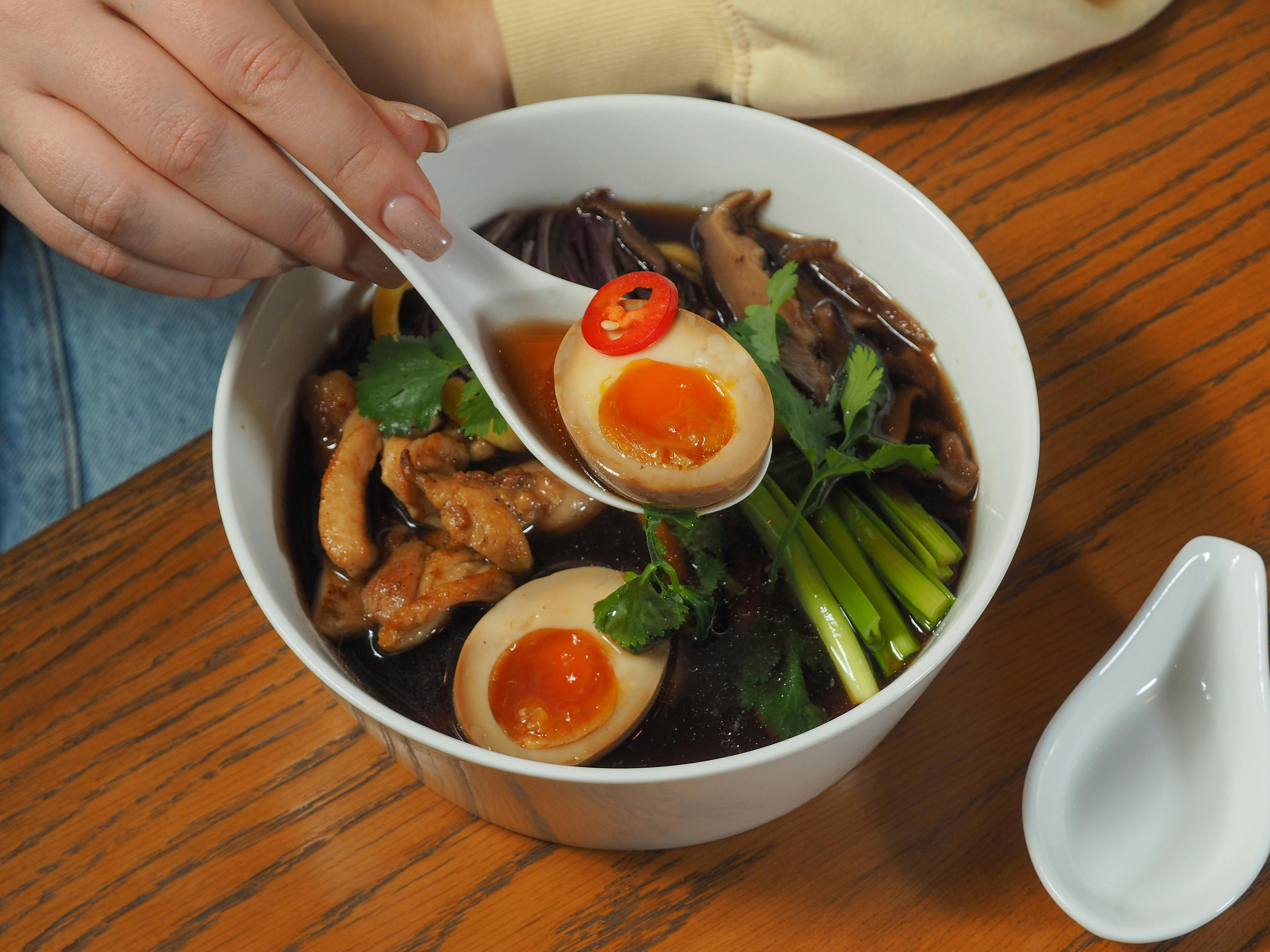 Savor the rich flavors of a freshly prepared ramen bowl with eggs and vegetables.
