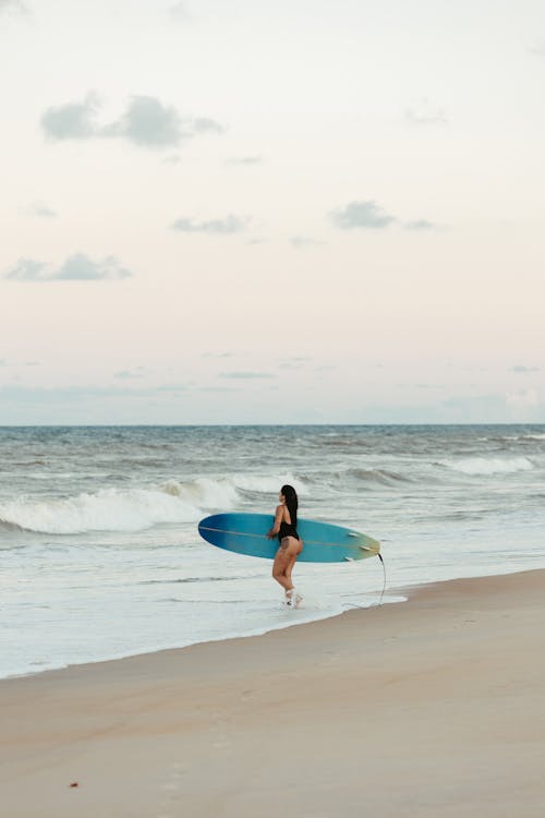 A Woman with a Surfboard at Sunset