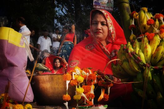 Colorful Chhath Puja celebration with women in traditional attire and offerings in Kolkata, India.