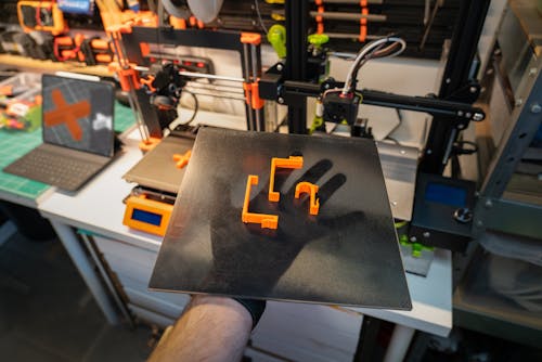 Man Holding a Tray with Plastic 3D Printed Items 