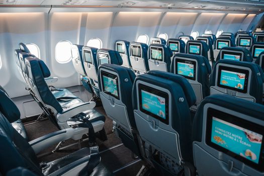 Empty airplane interior highlighting rows of seats with touchscreens, offering a modern in-flight experience.