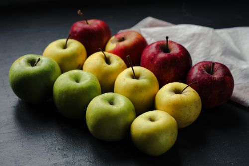 Free Colorful display of red, green, and yellow apples on a dark table. Stock Photo