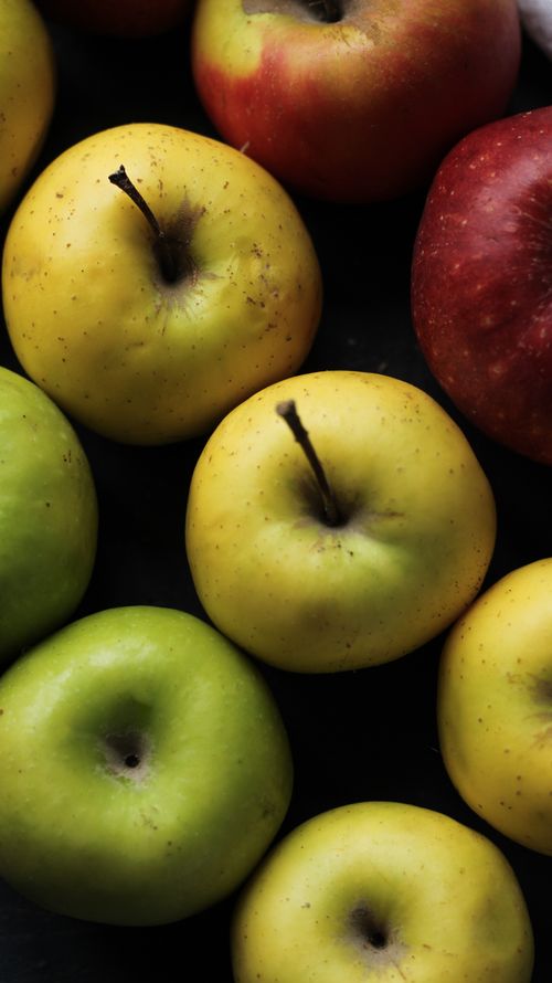 Free Close-up of colorful apples arranged on a dark surface, showcasing fresh nutrition. Stock Photo