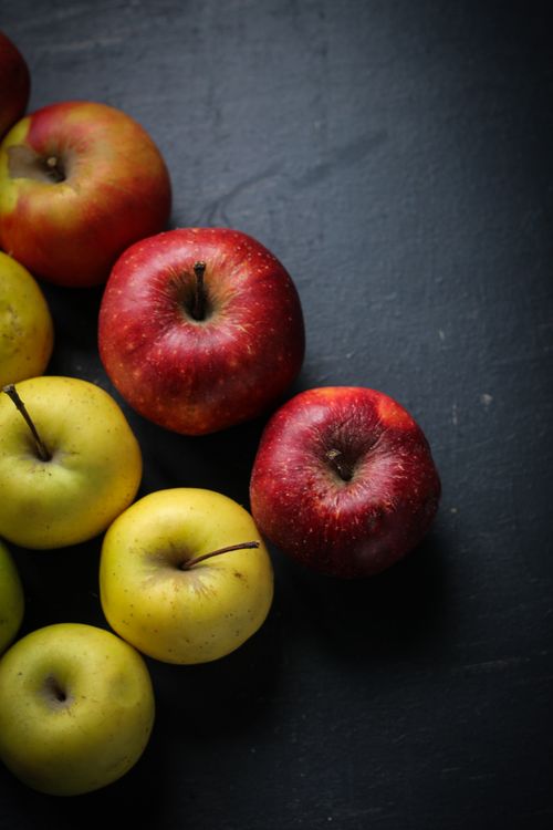 Free A vibrant still life of fresh red and green apples on a dark surface, highlighting organic nutrition. Stock Photo