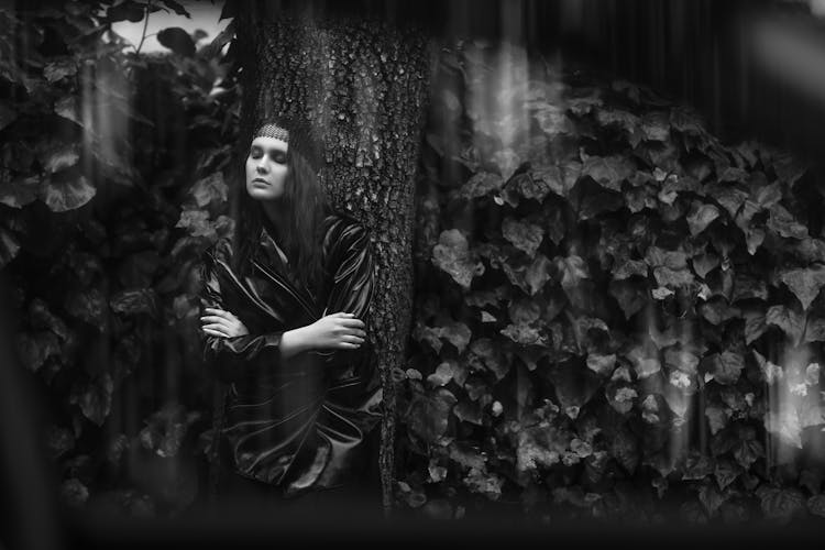 Woman Wrapped In Black Leather Jacket Leaning Against Tree 