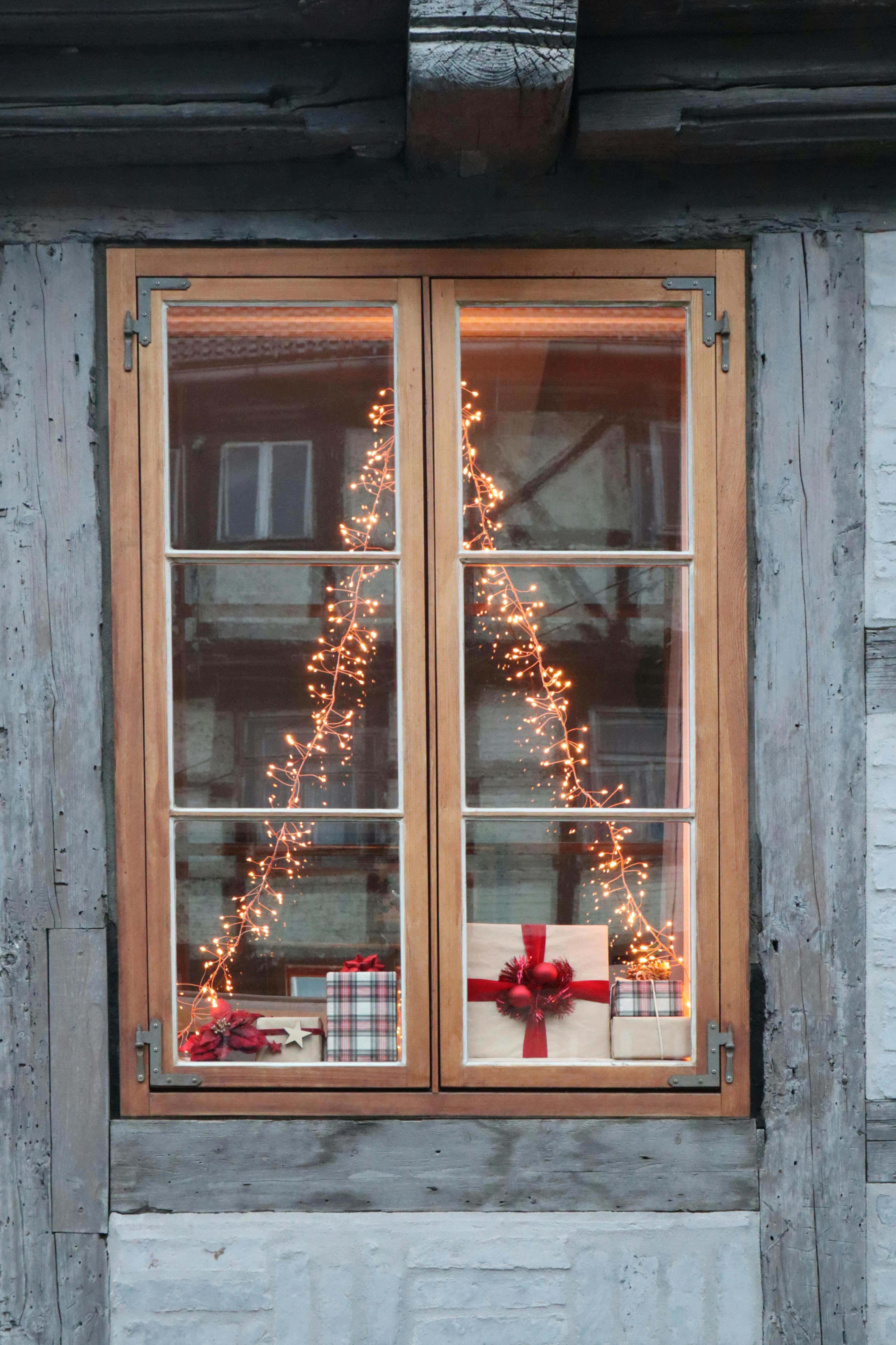 Festive Christmas gifts and lights seen through a quaint wooden window in Quedlinburg, Germany.