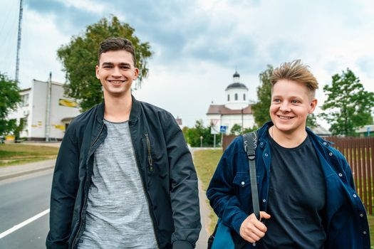 Two young men walking down the street with a sign that says, 'the best place to live'