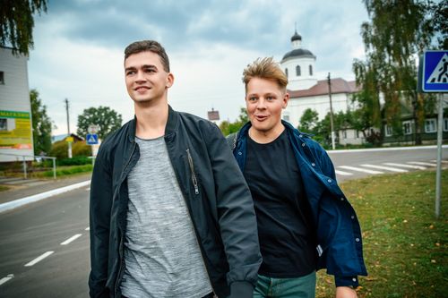 Free Two teenagers casually walking and smiling on a city street under a cloudy sky. Stock Photo