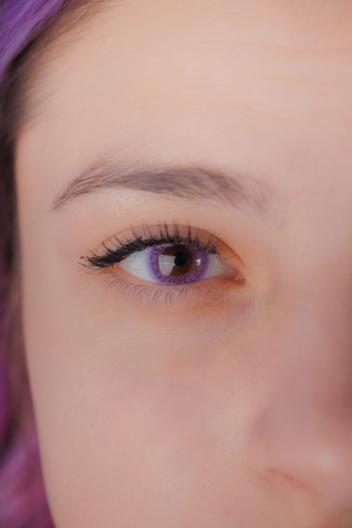 Free A detailed close-up of a young woman's eye featuring a purple contact lens. Stock Photo