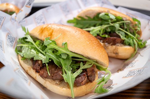 Savory beef sandwiches topped with fresh arugula served in soft bread.