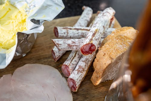 Close-up of Meat, Bread and Butter on a Wooden Cutting Board