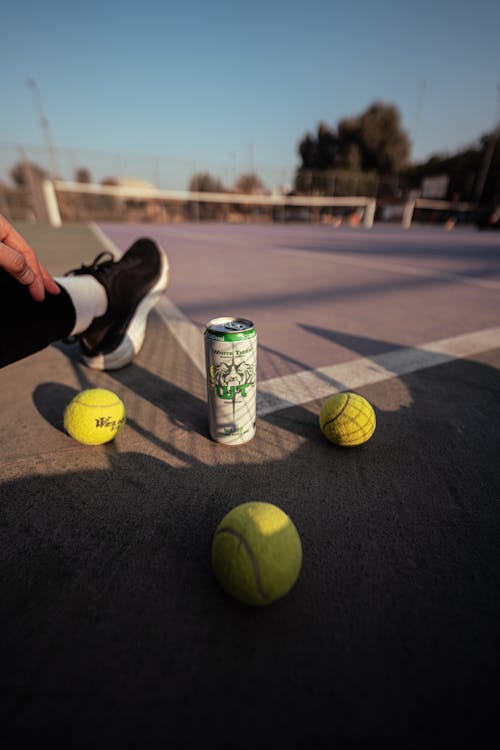 Tennis Balls and a Canned Drink on a Court