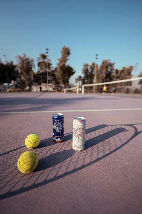 Free Tennis court with energy drink cans and tennis balls under clear skies. Stock Photo