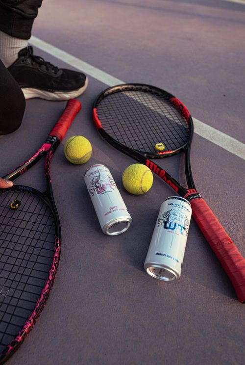 Free Tennis rackets and balls with energy drinks on a court. Perfect for sports and lifestyle themes. Stock Photo