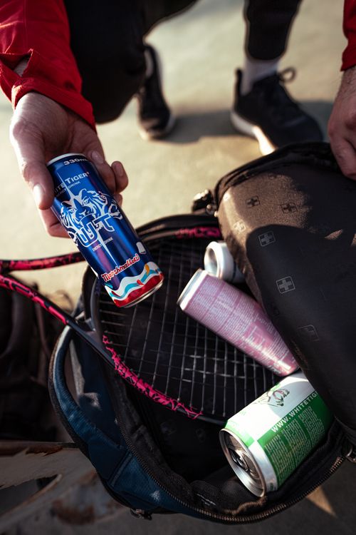 Free A person preparing for tennis with cans of energy drink and tennis gear in a backpack. Stock Photo