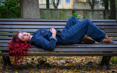 Woman Wearing Denim Dungarees Lying on Wooden Branch 