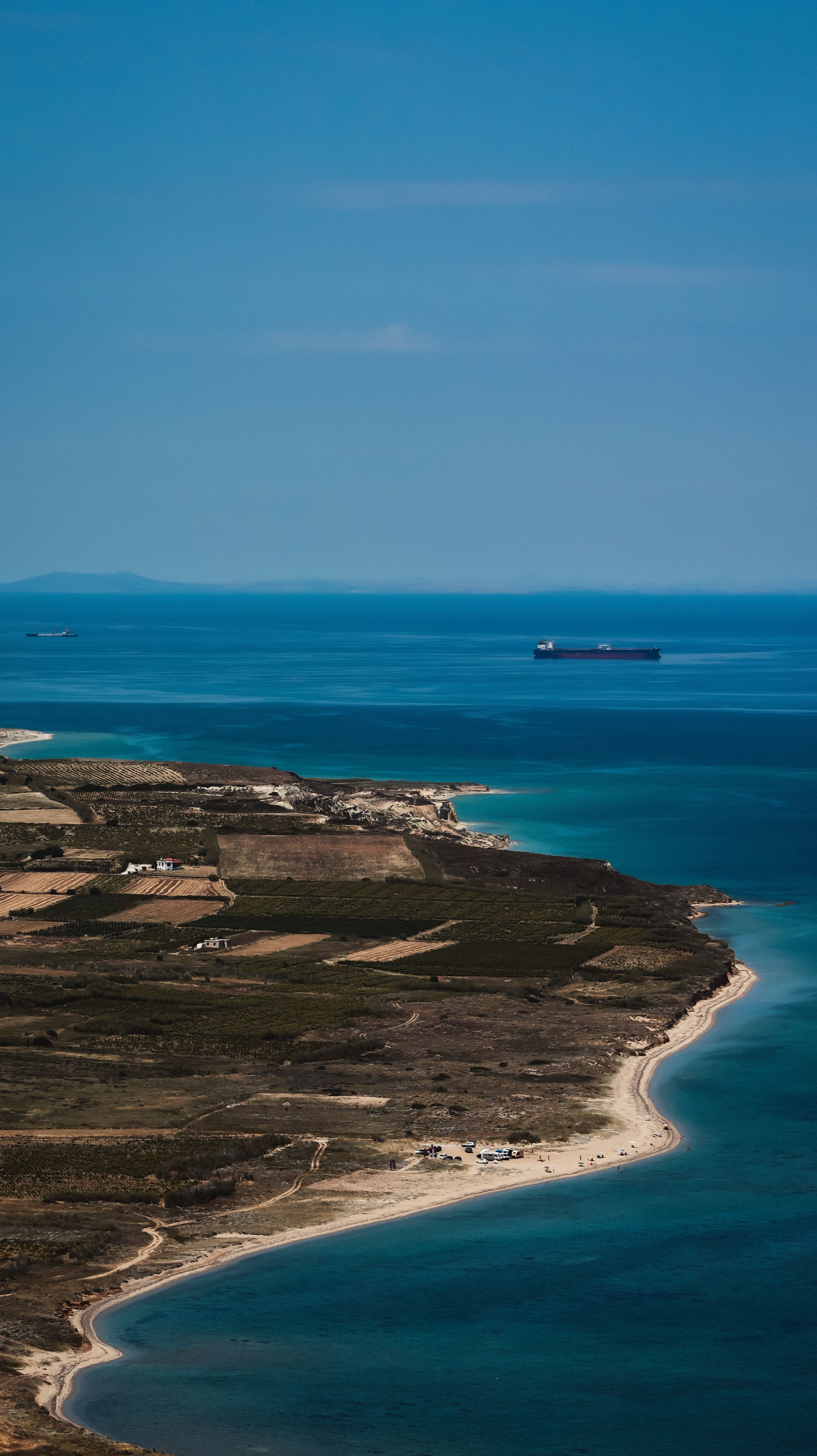 A stunning aerial shot of Bozcaada's coastline with clear blue sea and horizon.