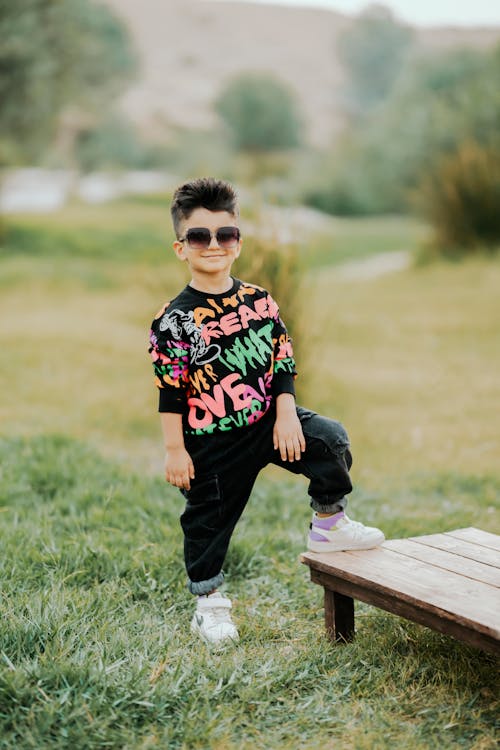 A Little Boy in a Trendy Outfit and Sunglasses Standing Outside 