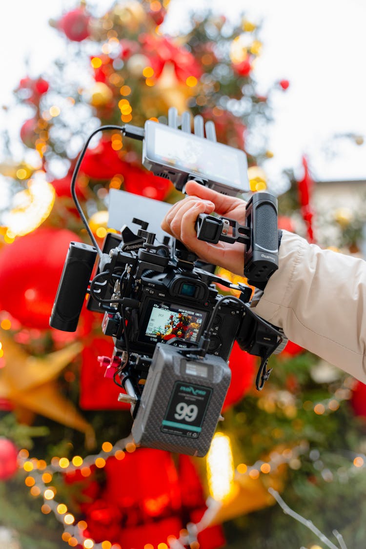 Close-up Of A Person Holding A Professional Camera Filming The Christmas Tree