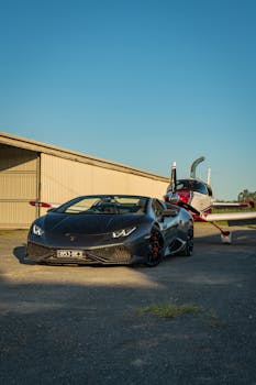 A sleek luxury sports car parked near a small private plane at Gold Coast Airport on a sunny day.