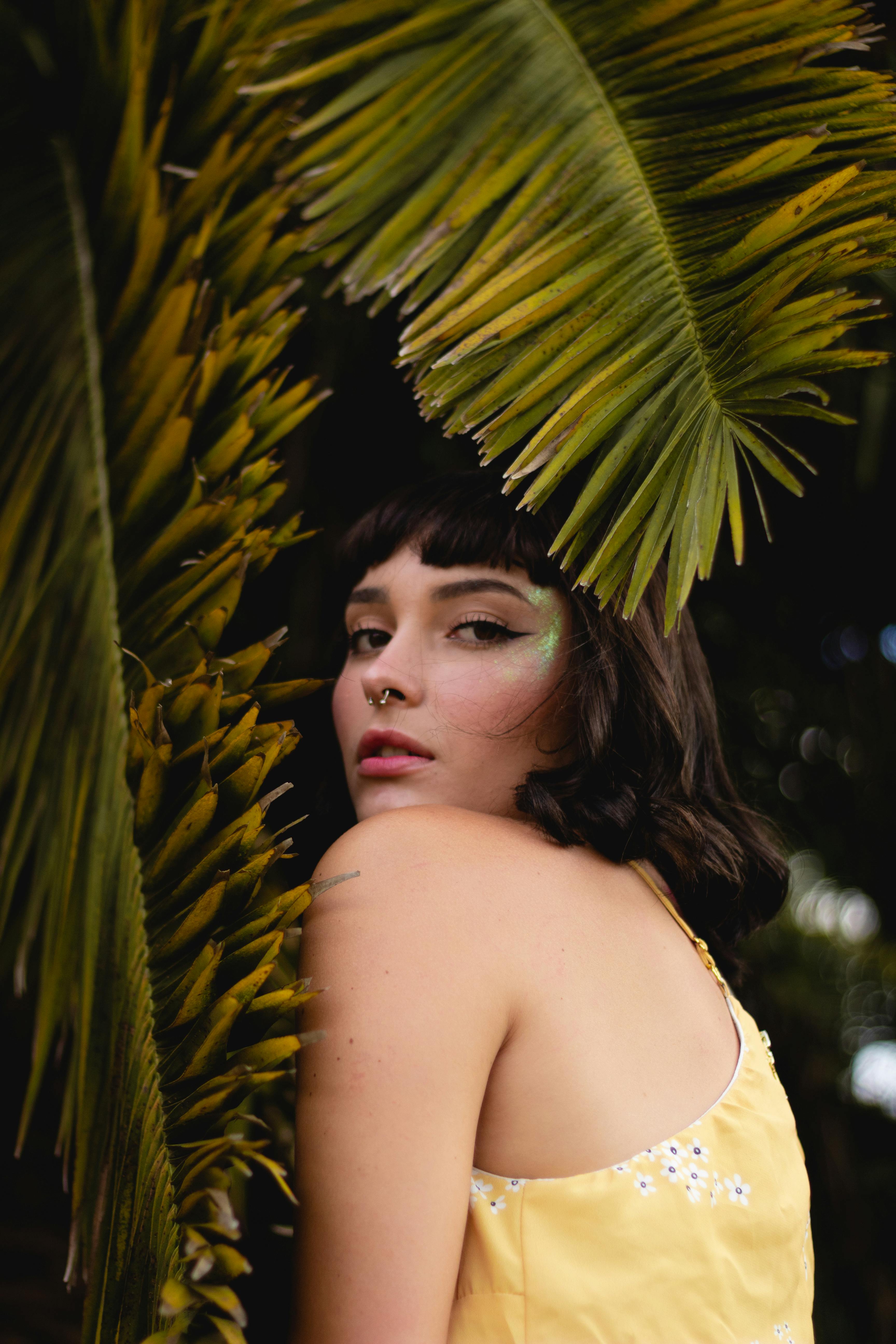 一位女士在热带树叶间摆姿势，展现自然之美与时尚