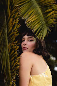 一位女士在热带树叶间摆姿势，展现自然之美与时尚