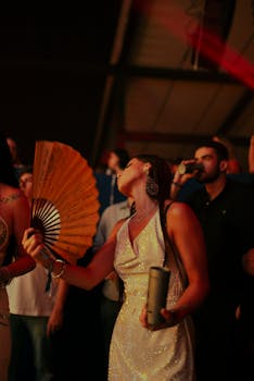 Energetic woman dancing with a fan at a lively concert, highlighting nightlife fun and excitement.