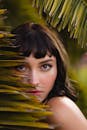 热带棕榈叶环绕着一位女士的特写肖像，营造出神秘而自然的氛围