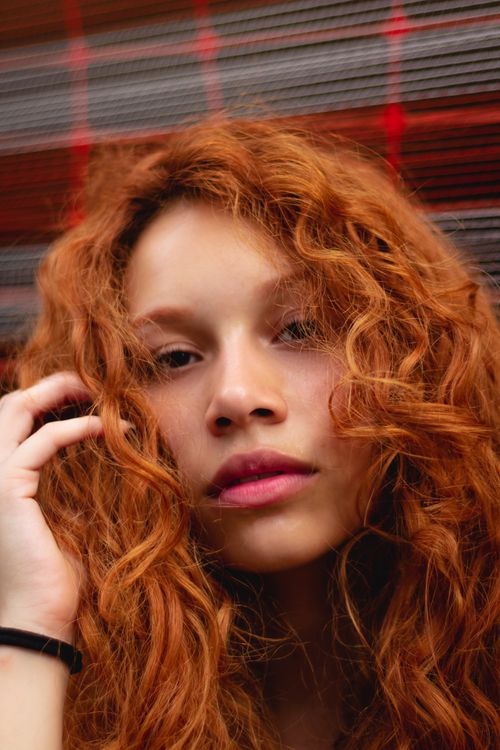Free Beautiful portrait of a young woman with vibrant red curly hair. Stock Photo