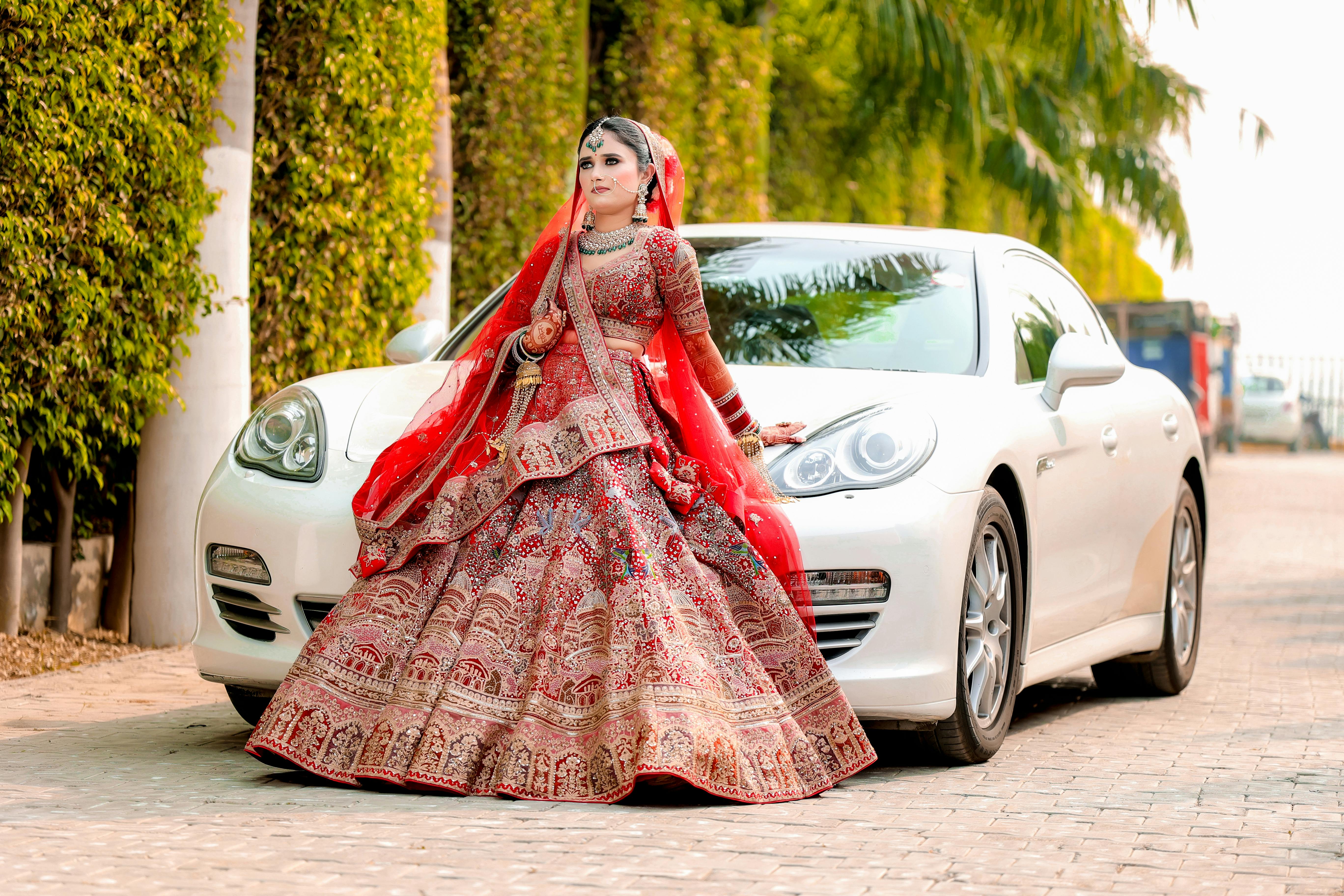 free photo of indian bride in a lehenga standing in front of a car