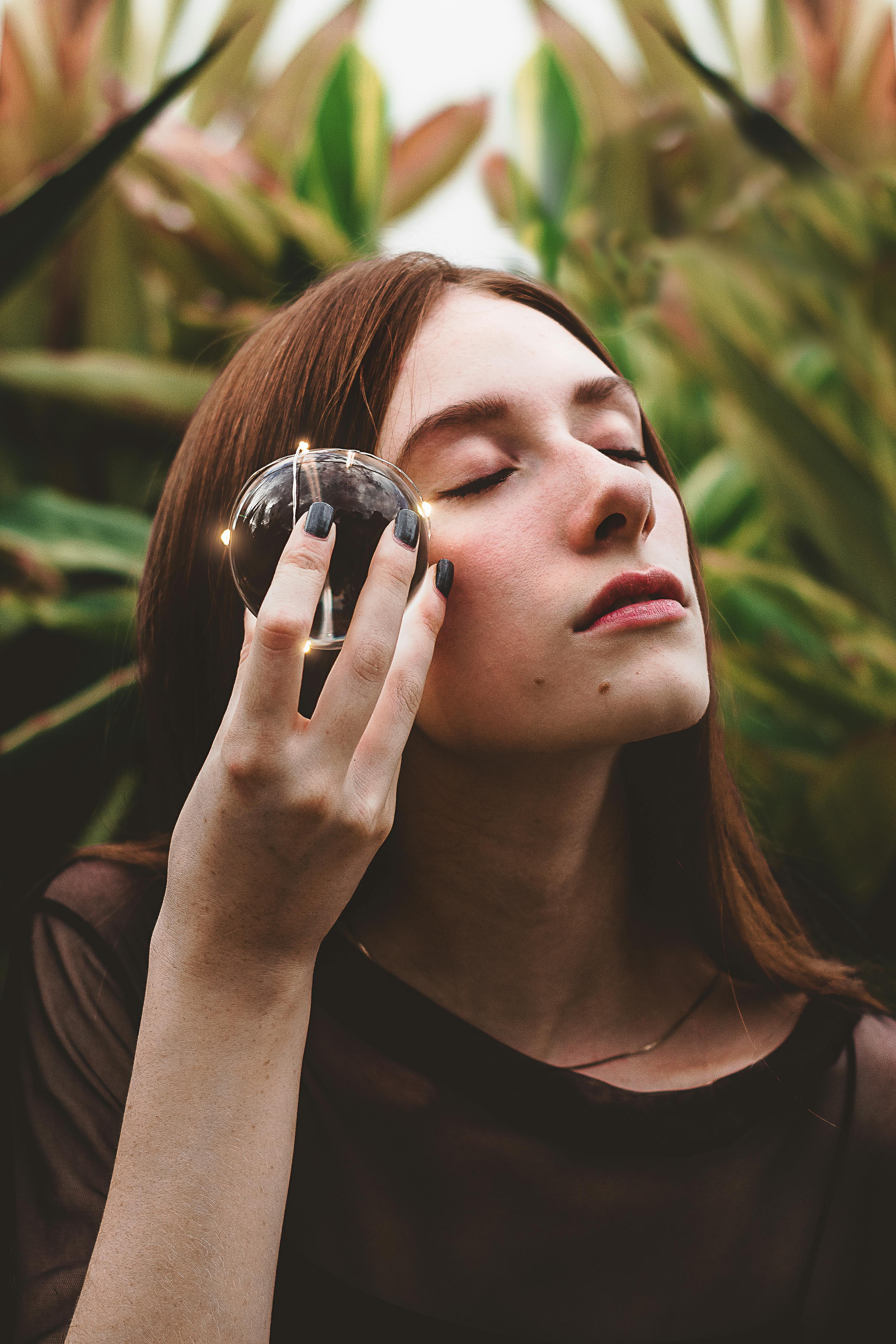 一名年轻女子在宁静的户外环境中闭目静思，手持水晶球