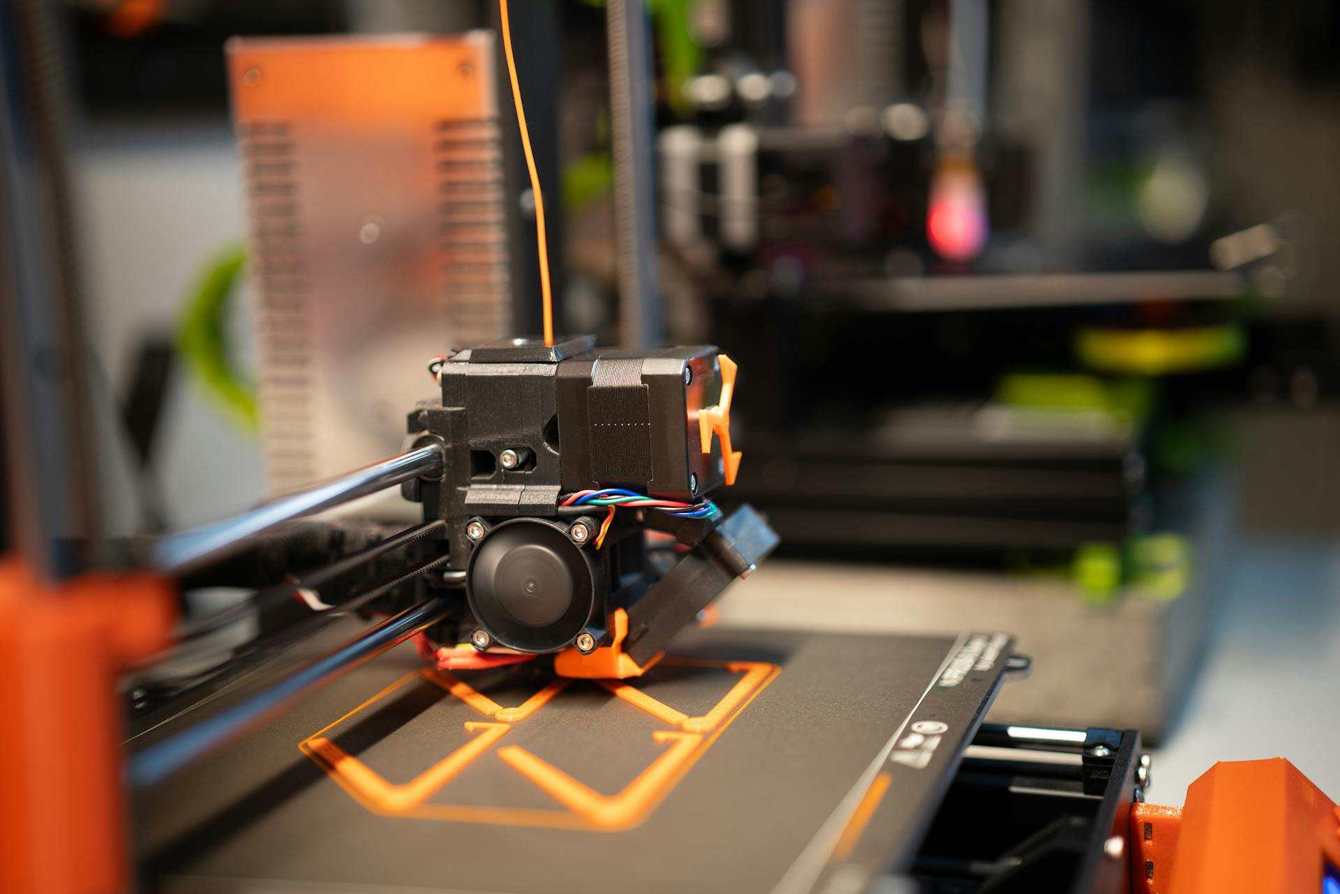 Detailed view of a 3D printer head in action creating a design.