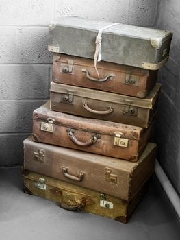 A stack of vintage suitcases in a corner with a rustic aesthetic.
