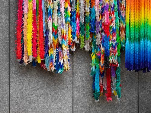 Free Vibrant origami cranes hanging on a wall in Tokyo offer a burst of color and artistry. Stock Photo