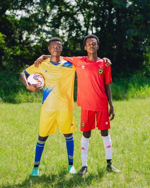 Free Two young soccer players in vibrant uniforms standing together on a sunny field. Perfect for sports and teamwork themes. Stock Photo