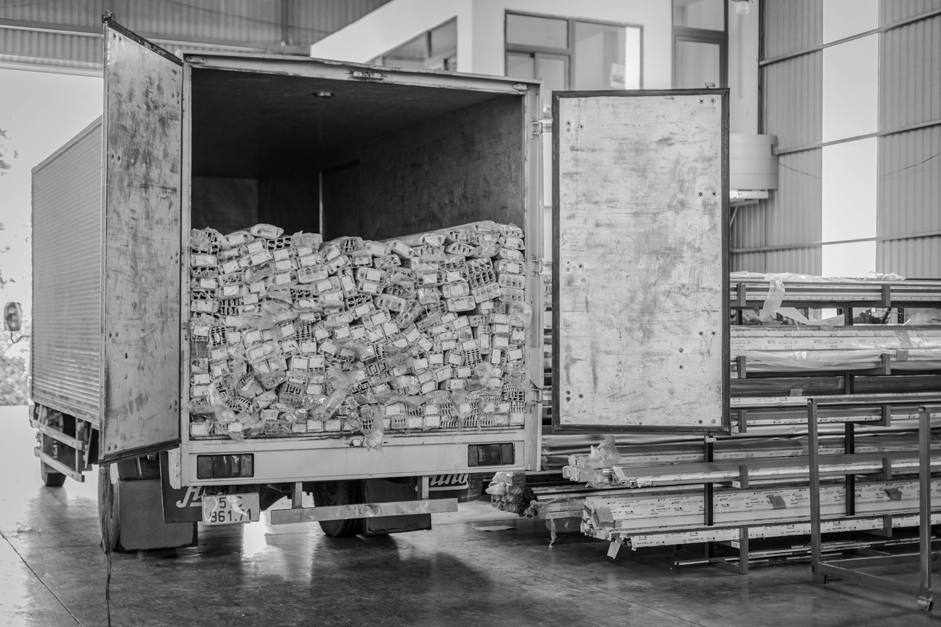 Black and white image of an open delivery truck in an indoor warehouse setting.