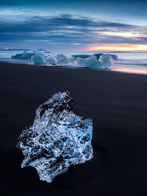 Un Iceberg Cristallino Lavato Sulla Sabbia Nera Vulcanica Della Spiaggia Di Jökulsárlón, Islanda (Laguna Dei Ghiacciai). Questa Immagine è Stata Scattata All'alba.