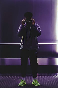 一名穿着活力运动鞋的时尚男子在灯火通明的城市电梯里摆出姿势