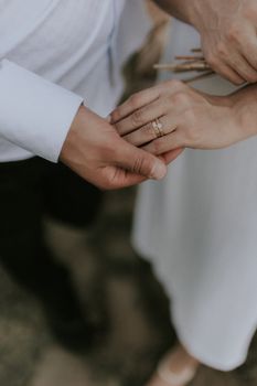 Close-up of a couple holding hands, showcasing elegant wedding rings on their fingers.