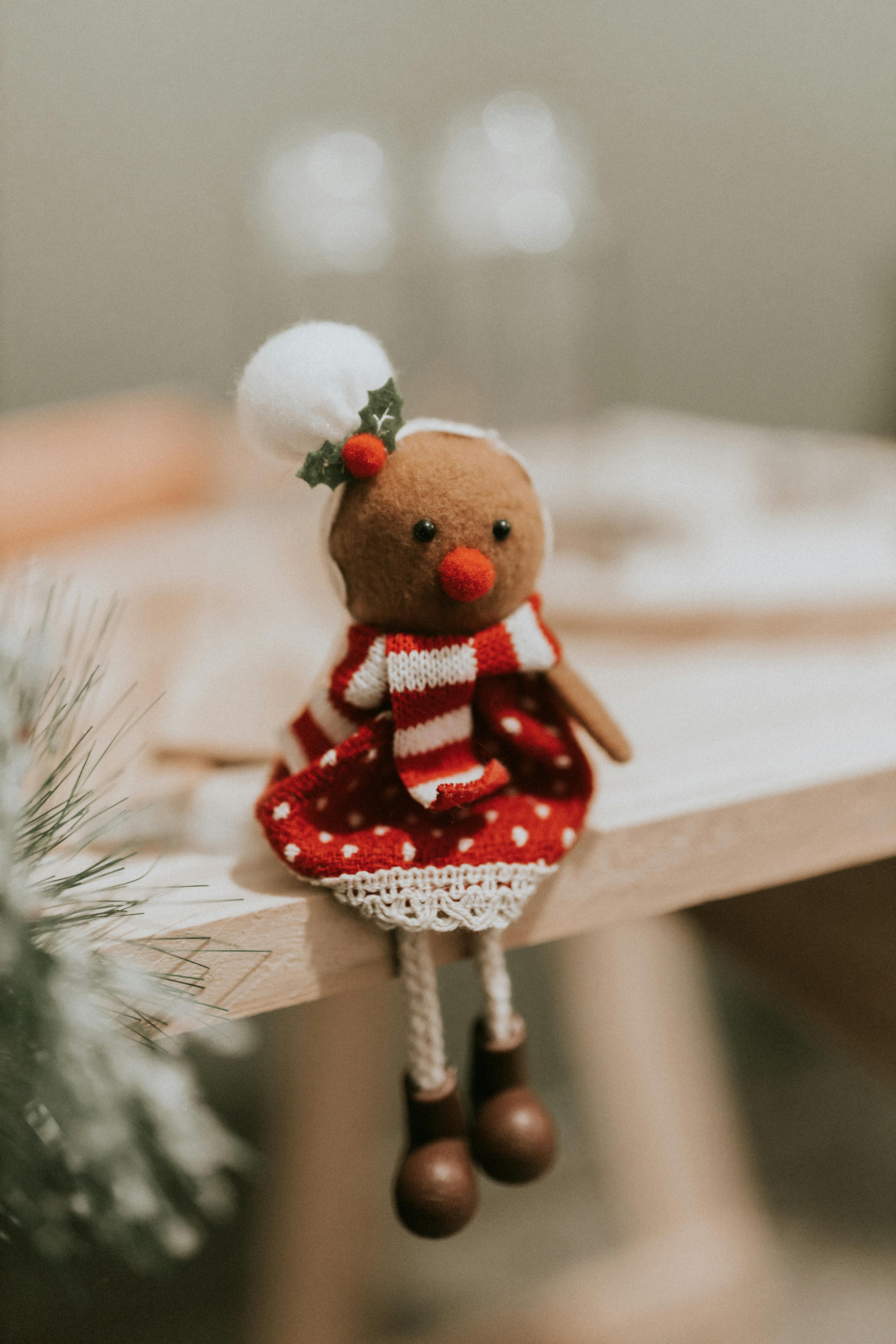 Cute gingerbread man decoration in holiday attire sitting on a wooden surface, perfect for Christmas.