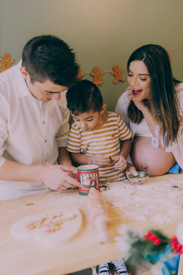 Pregnant Woman Making Cookies Together With Man And Boy 