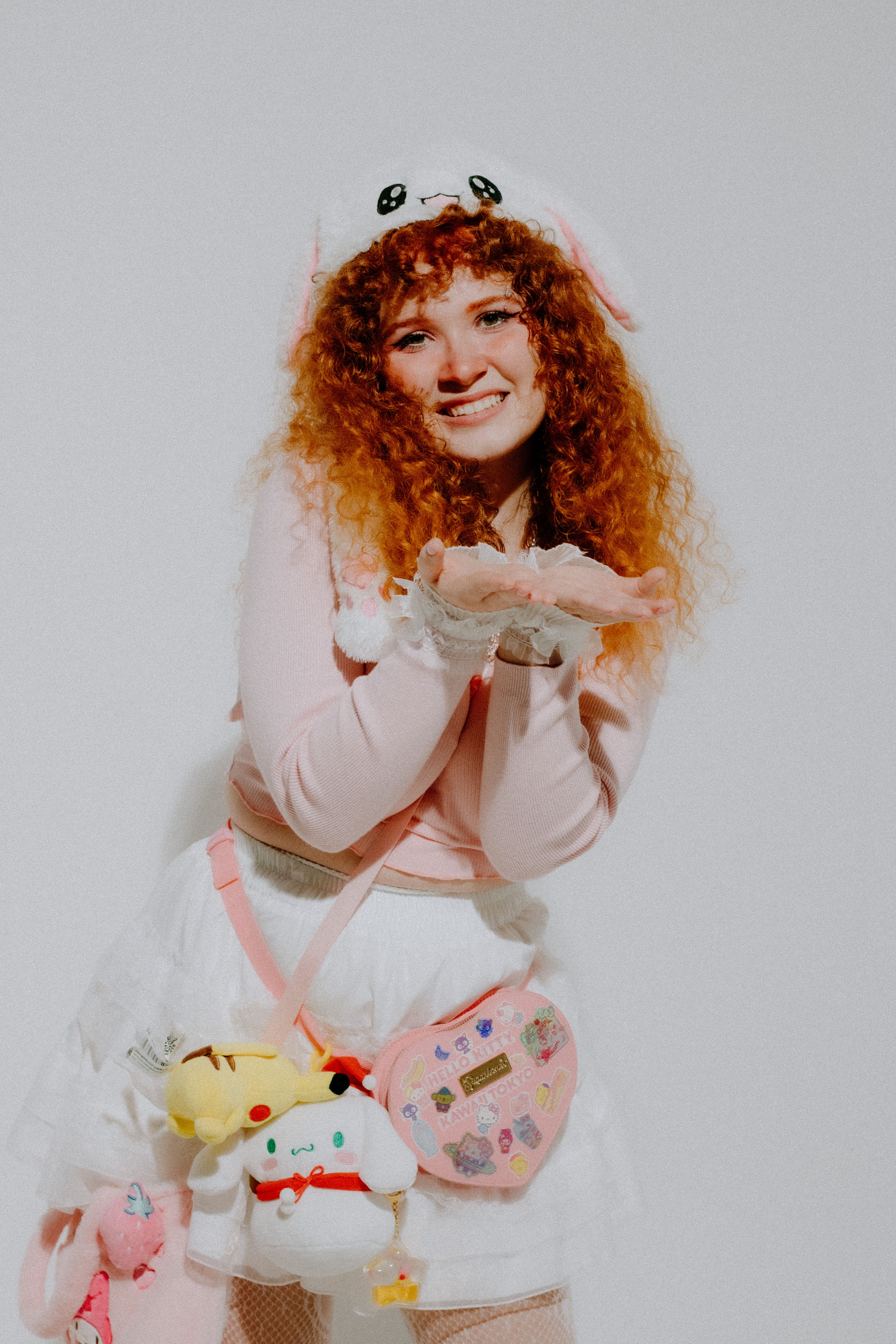 A joyful redhead posing in kawaii fashion with playful accessories in a studio setting.