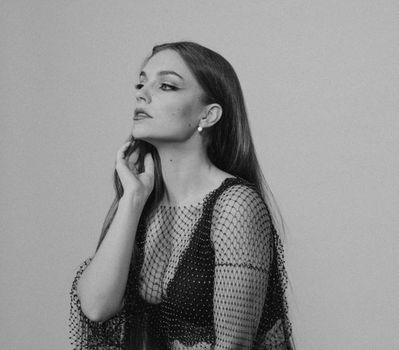 Stylish black and white portrait of a woman in a netted dress, exuding elegance.