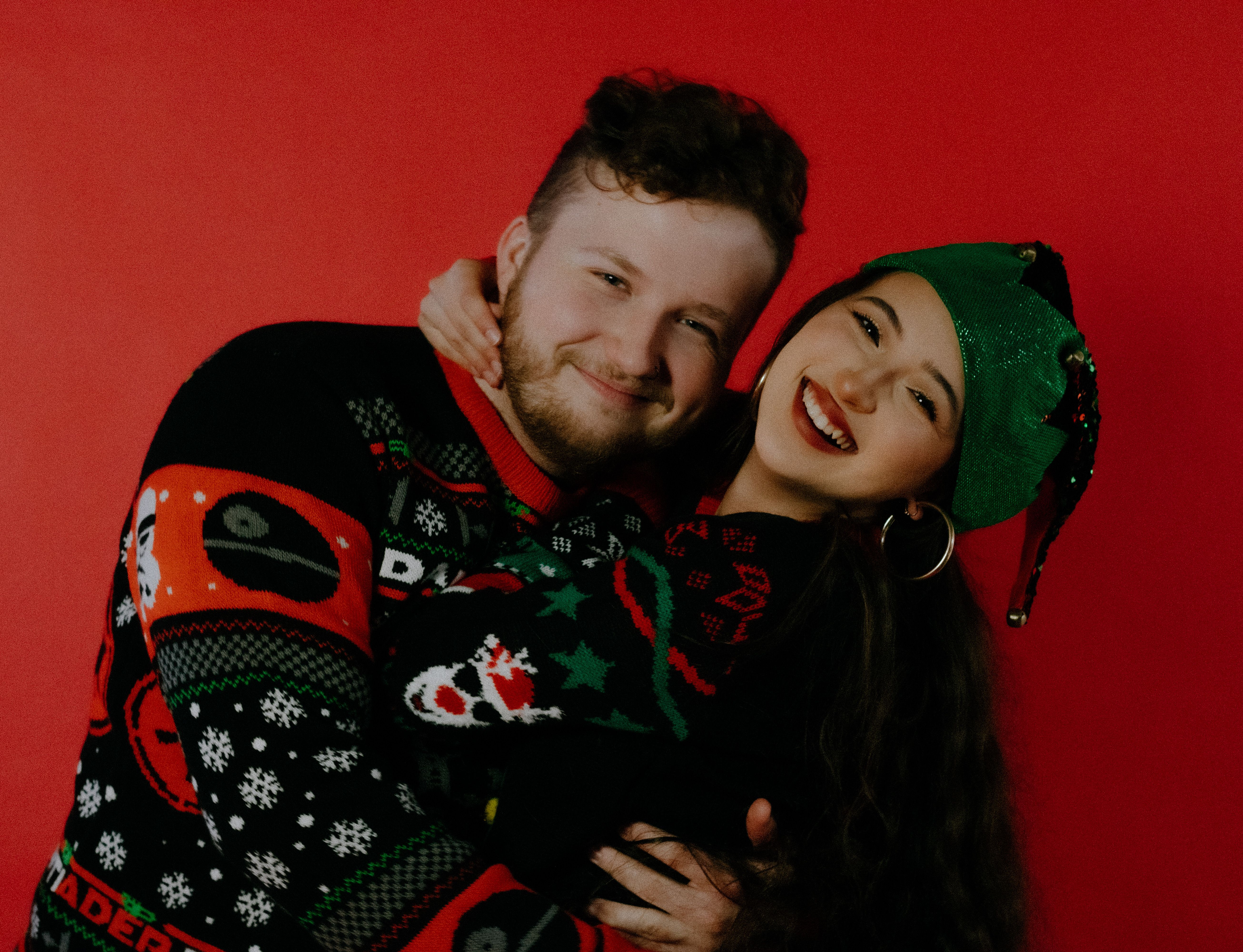 Happy couple in festive sweaters celebrating Christmas with smiles and warmth.