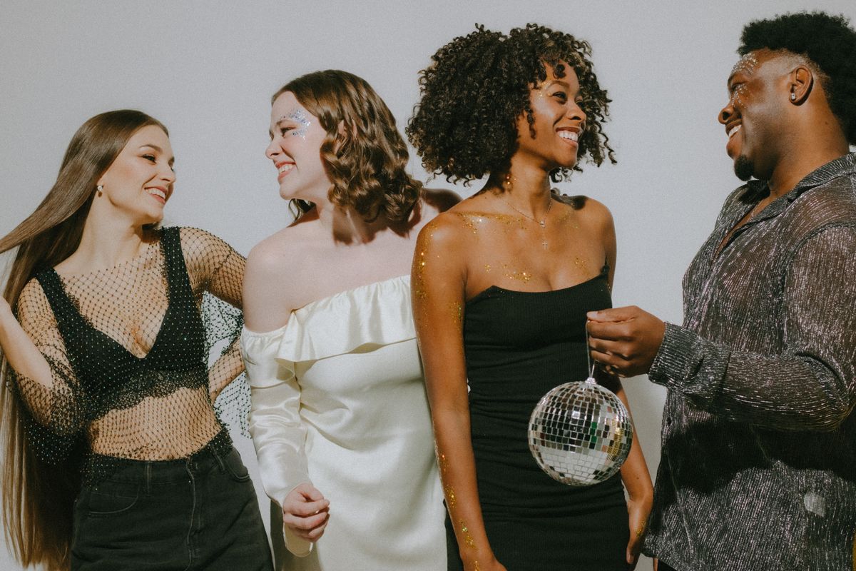 Grupo de amigos celebrando una fiesta con ropa llamativa y bola de discoteca