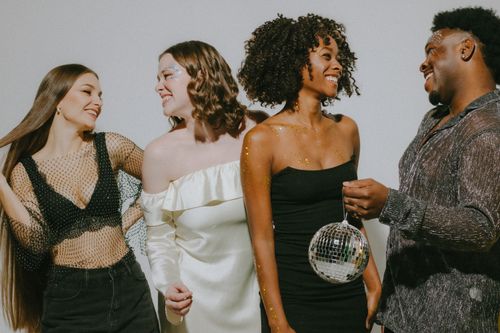 Free Group of friends enjoying a lively party, smiling and holding a disco ball, embodying nightlife fun. Stock Photo