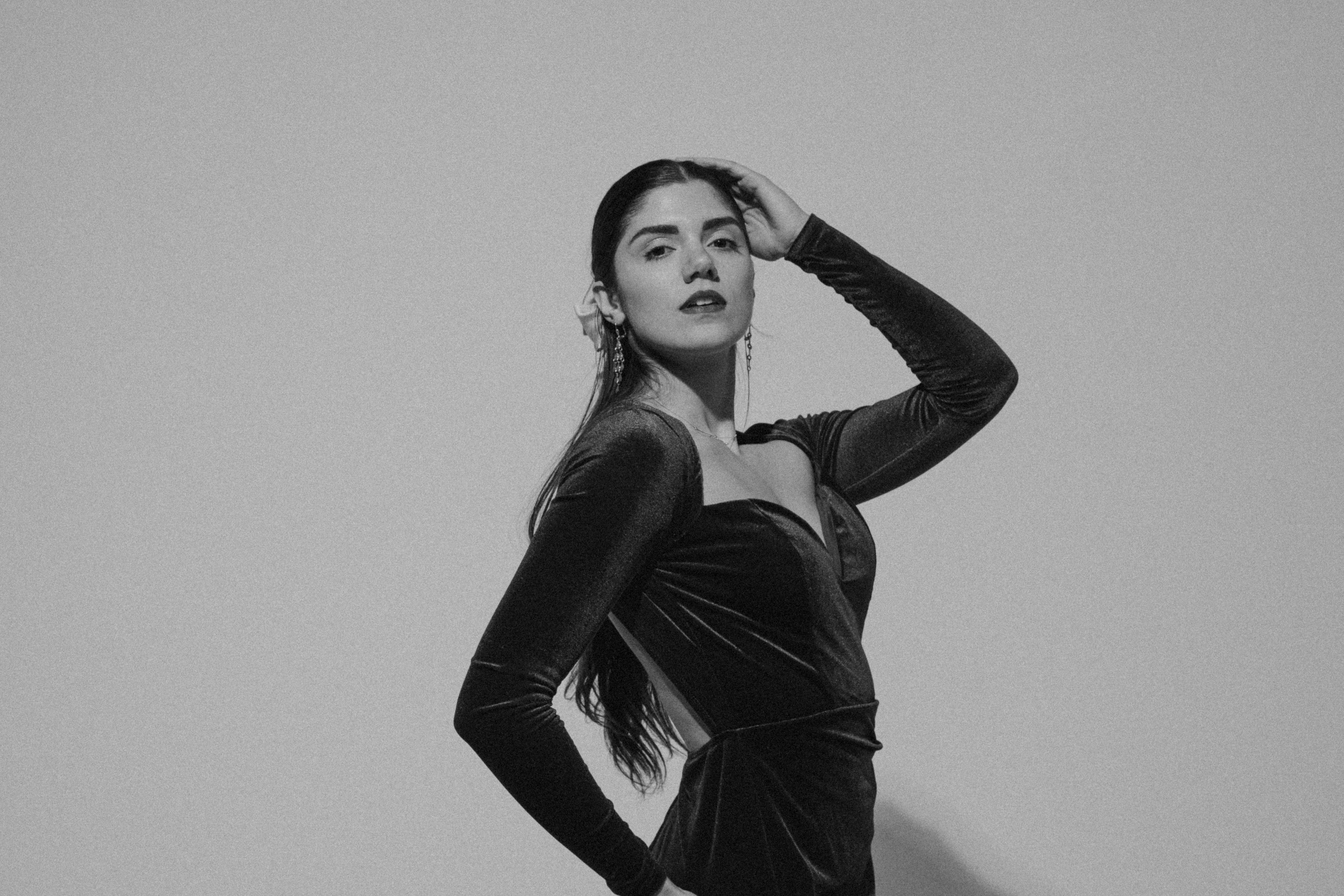 Free A glamorous black and white studio portrait of a woman posing in a fashionable dress. Stock Photo