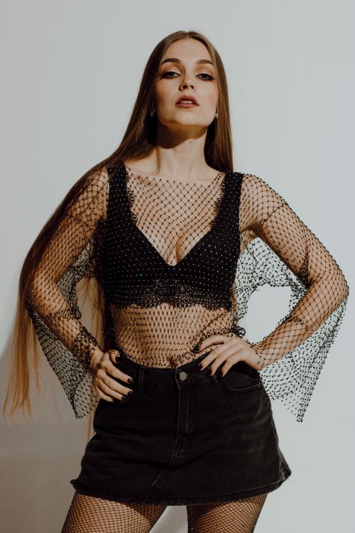 Free Fashionable model posing confidently in studio, wearing chic black lingerie and mesh outfit. Stock Photo